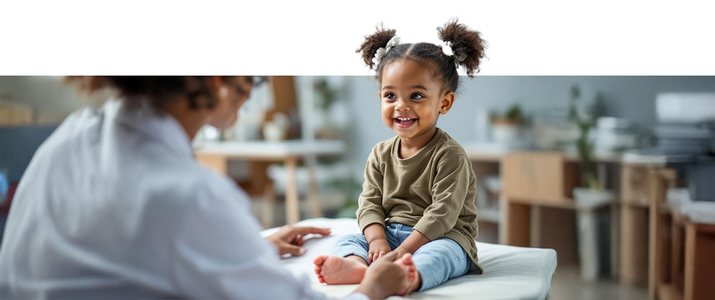 A smiling toddler is being examined for immediate care at Quality Care Pediatrics during a same-day appointment in Stonecrest, GA.