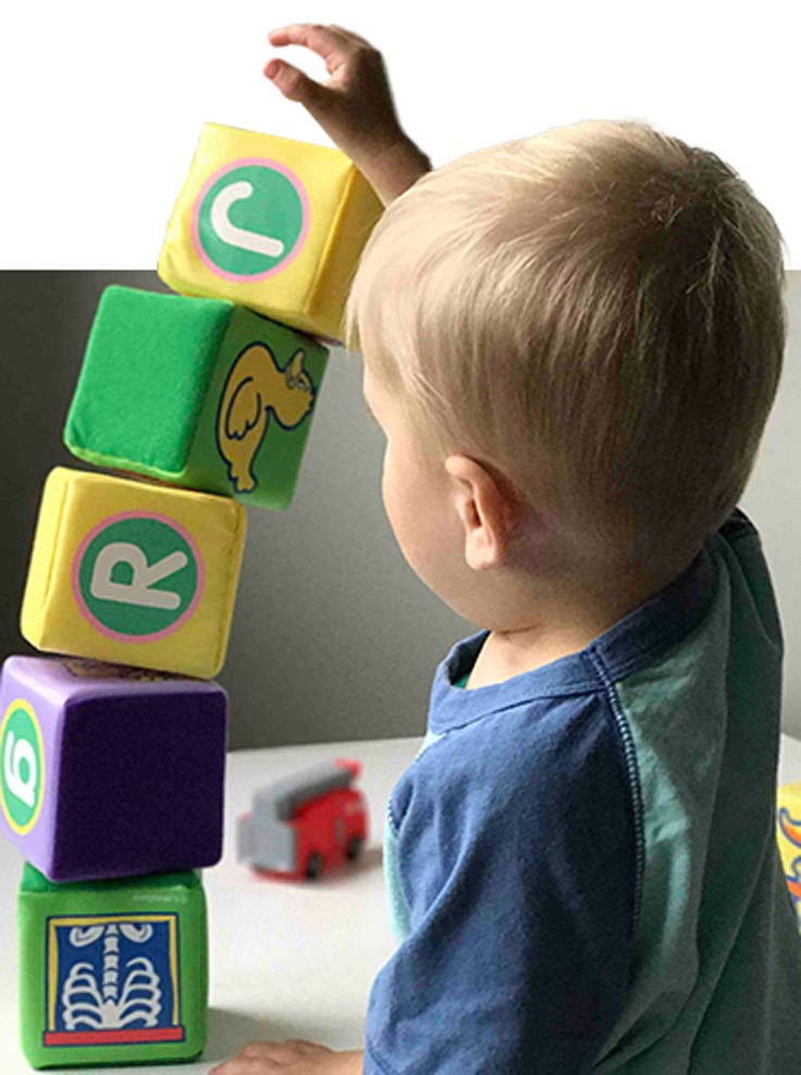 A toddler boy is playing with blocks in the waiting room at Quality Care Pediatrics in Stonecrest, GA. a place of healing, education, and dependable care for growing children.